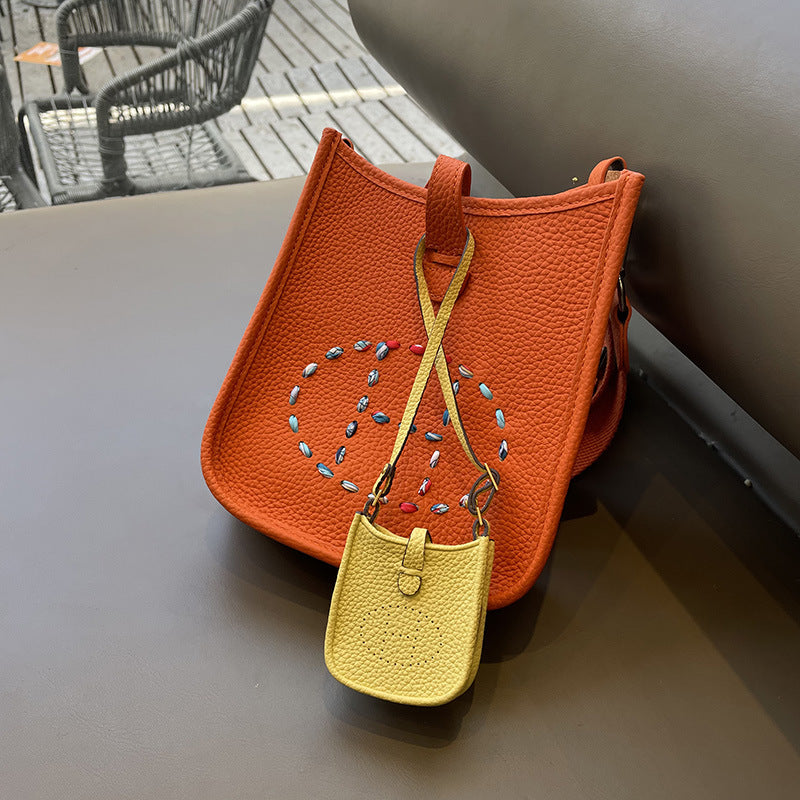 Yellow mini Eveline bag charm on orange leather handbag accessory.