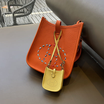 Yellow mini Eveline bag charm on orange leather handbag accessory.
