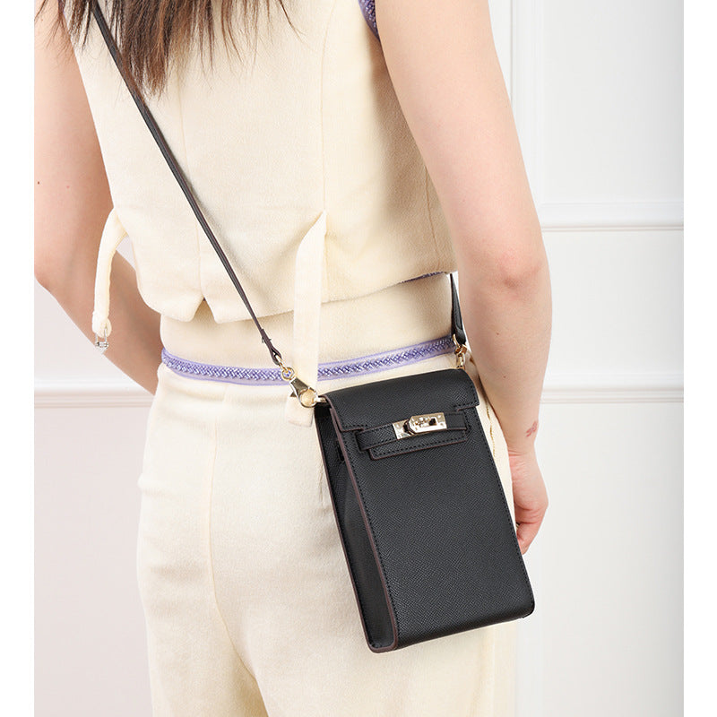 Model wearing a black genuine leather mini phone bag with Kelly-style gold lock as a crossbody bag.