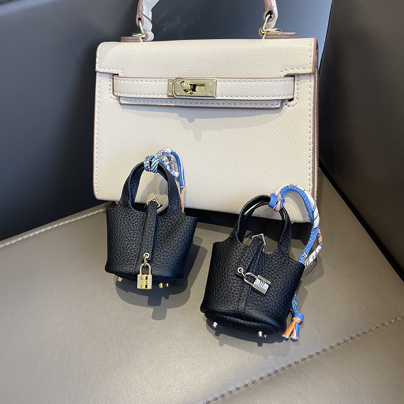 Black mini leather Picotin bag charms with silk ribbon on white handbag.