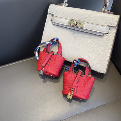 Red mini leather Picotin bag charms with silk ribbon on white handbag.
