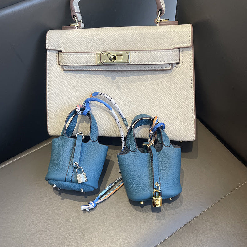Blue mini leather Picotin bag charms with silk ribbon on white handbag.