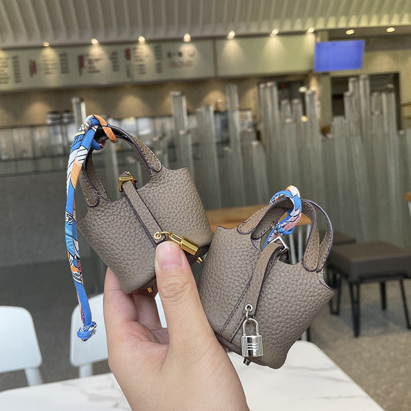 Taupe mini leather Picotin bag charms with silk ribbon and lock detail.