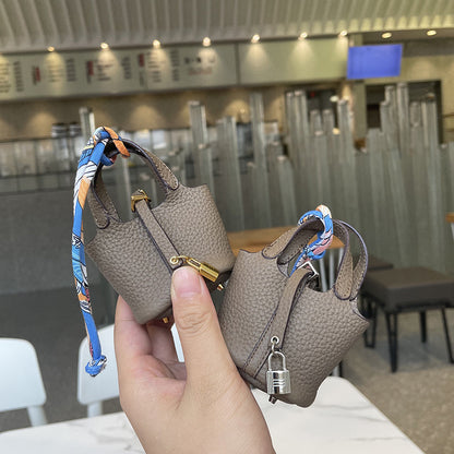 Taupe mini leather Picotin bag charms with silk ribbon and lock detail.
