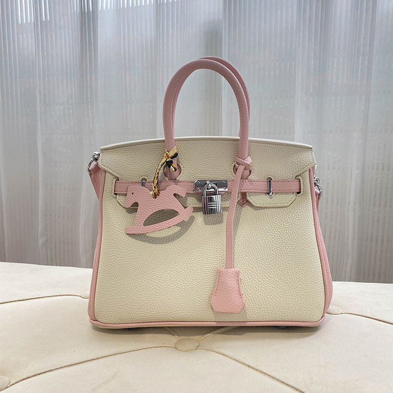Front view of a bi-color Pink and White inspired Birkin handbag in premium top grain leather, featuring a silver twist lock and a matching pink horse charm.