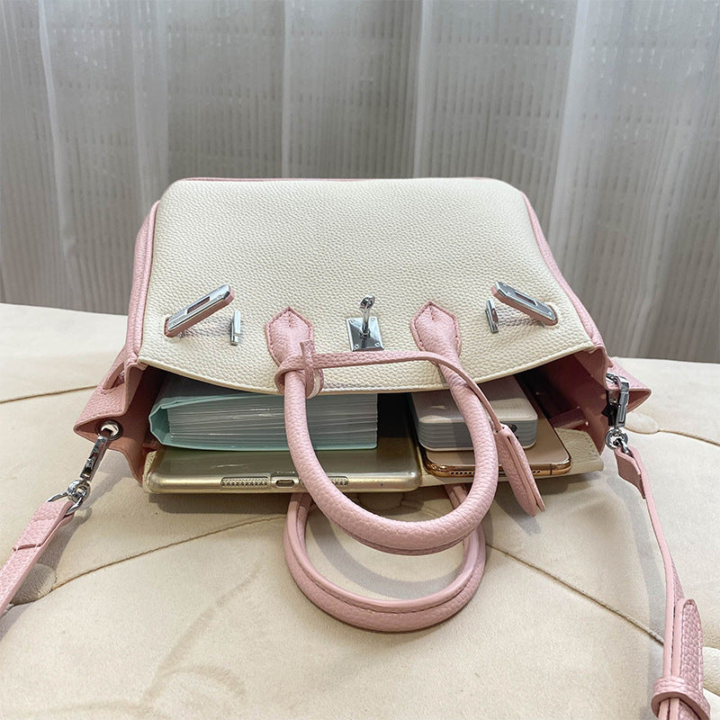 Interior view of a bi-color Pink and White inspired Birkin handbag in top grain leather, showcasing its spacious compartment filled with daily essentials like a wallet, phone, and notebooks.
