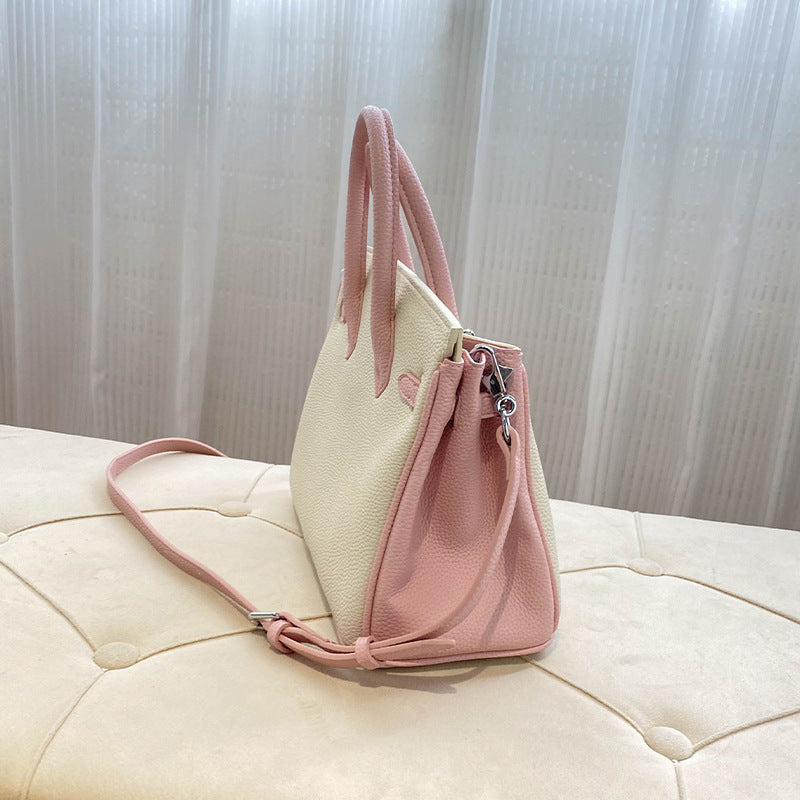 Side view of a bi-color Pink and White inspired Birkin handbag in textured top grain leather, highlighting the expandable gusset, double rolled handles, and matching pink shoulder strap.