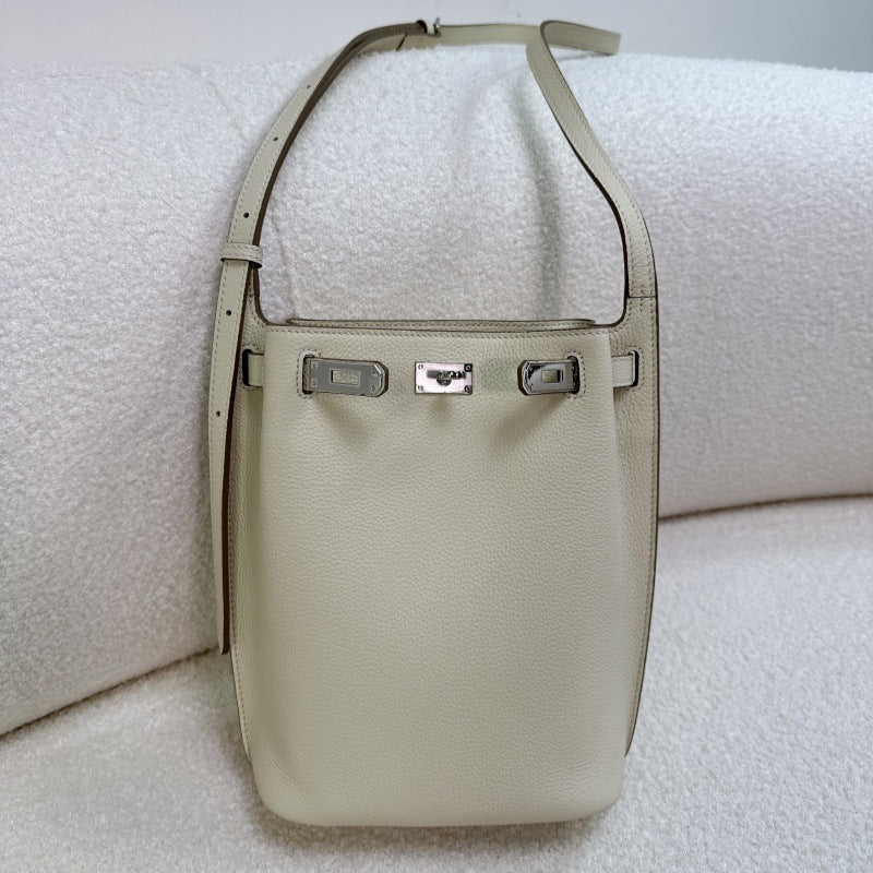 Off-white pebbled top-grain leather Kelly bucket bag with silver turn-lock hardware and adjustable shoulder strap.