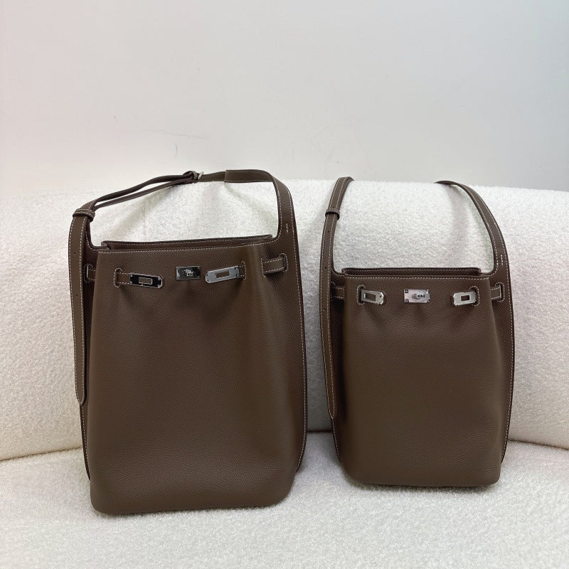 Mini and small Taupe pebbled top-grain leather Kelly bucket bags with silver hardware and adjustable shoulder straps.
