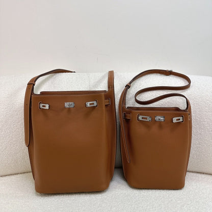 Mini and small Gold Brown pebbled top-grain leather Kelly bucket bags with silver turn-lock hardware and adjustable shoulder straps.