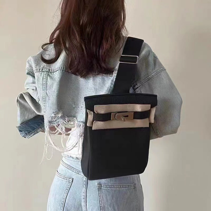 A model wearing a black and beige Unisex Togo FannyPack as a crossbody backpack, showcasing its 26cm height and adjustable fabric strap over a denim jacket.