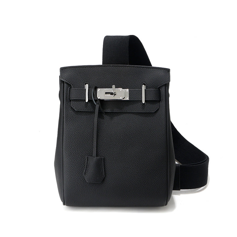 Front view of the black Unisex Togo FannyPack in pebbled top grain leather, featuring a silver turn-lock closure and a wide black fabric crossbody strap.