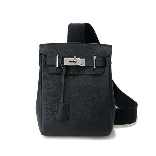 Front view of the black Unisex Togo FannyPack in pebbled top grain leather, featuring a silver turn-lock closure and a wide black fabric crossbody strap.