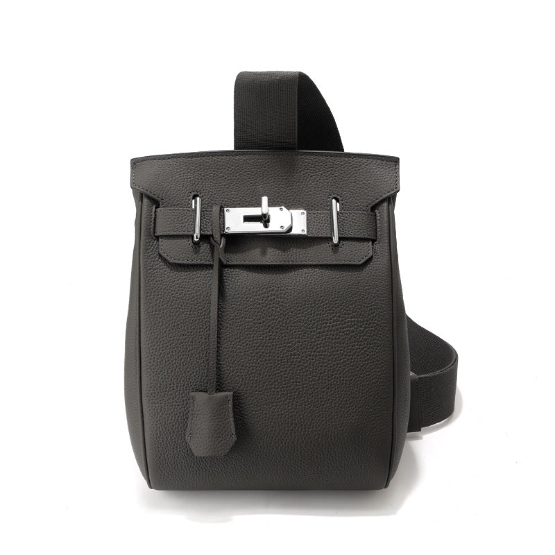 Front view of the Gris Etain Unisex Togo FannyPack in pebbled top grain leather, featuring a silver turn-lock closure and a wide black fabric crossbody strap.