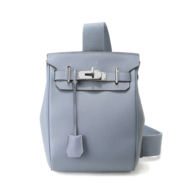 Front view of the Linen Blue Unisex Togo FannyPack in pebbled top grain leather, featuring a silver turn-lock closure and a wide black fabric crossbody strap.