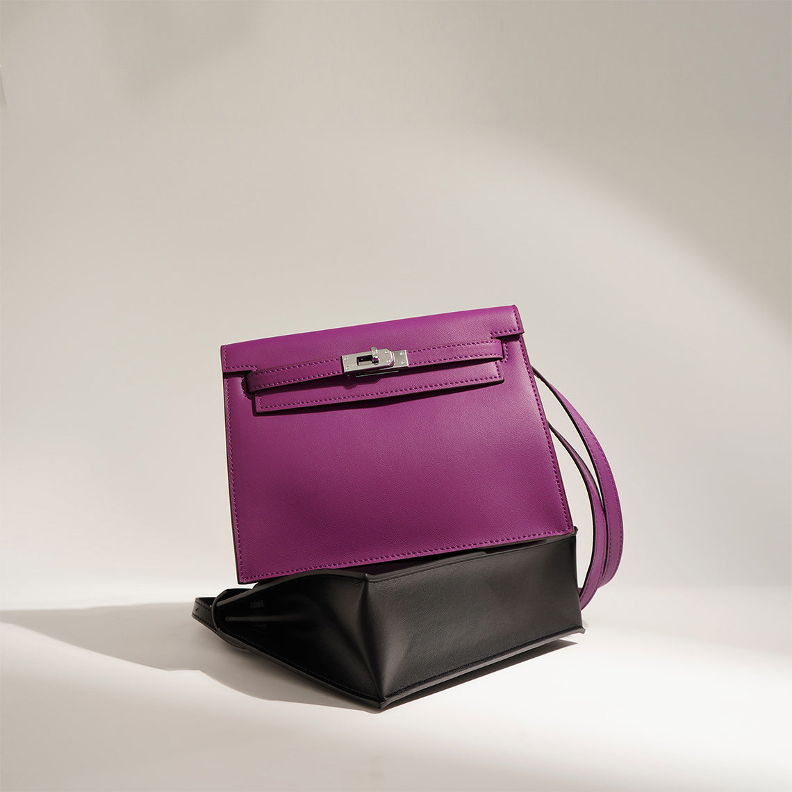 Purple and black Kelli Danse top grain leather bags stacked together, showcasing the two elegant colorways with silver hardware.