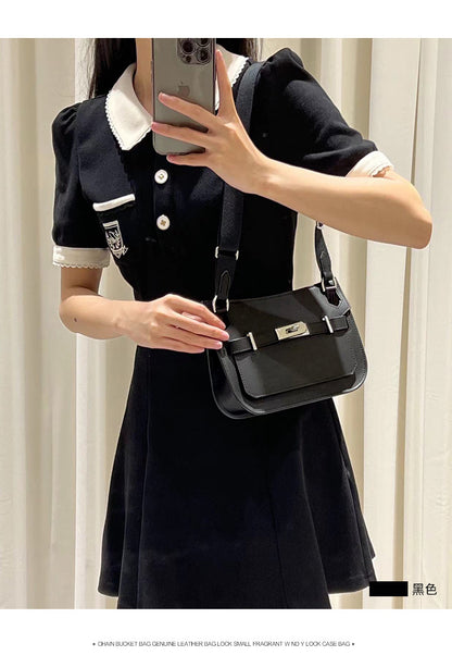 A woman wearing a black collegiate-style dress styled with a black leather Gypsy shoulder bag, showcasing a sleek, all-black monochromatic look.